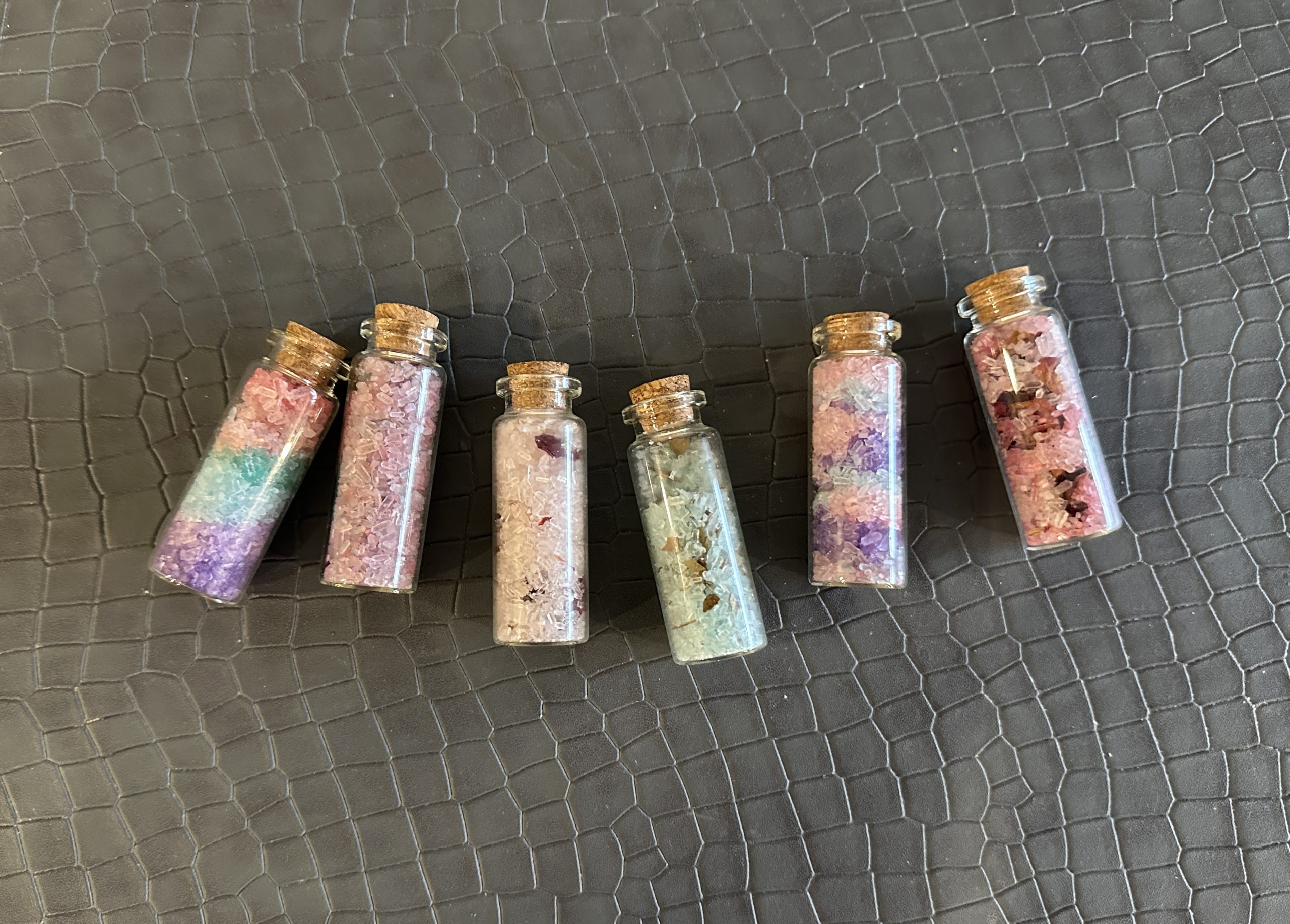 Spread of glass vials with colourful epsom salts in various styles.